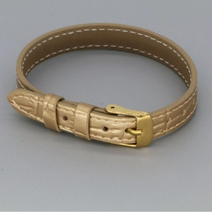 Detail of champagne gold leather strap bracelet with metallic buckle and stitching