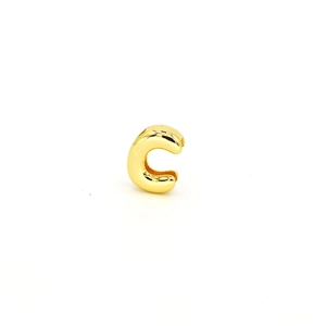 Close-up of polished gold-plated C-letter charm bead with hole for DIY jewelry making