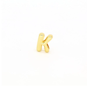 Detailed view of bubble style gold letter K charm with high-polished metallic surface