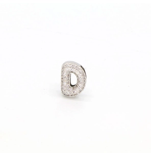 Detailed macro of silver-colored letter D charm with micro-paved sparkling zircon stones