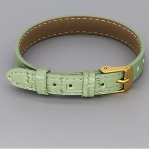 Detail of light green crocodile-pattern leather bracelet with gold-tone metal pin buckle