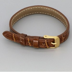 Detail of brown crocodile embossed leather strap with gold buckle and white stitching