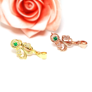 Close-up of gold and rose gold pendant clips with green stones and diamond accents