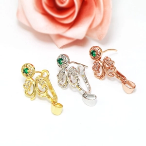 Macro shot of 18k gold plated flower-shaped jewelry pendant clasps with green gemstone