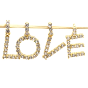 Macro shot of gold alphabet pendants L O V E encrusted with sparkling cubic zirconia stones