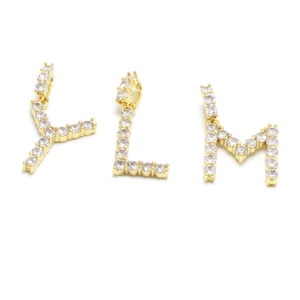 Detail of gold letter pendants Y, L, and M encrusted with sparkling round cut stones