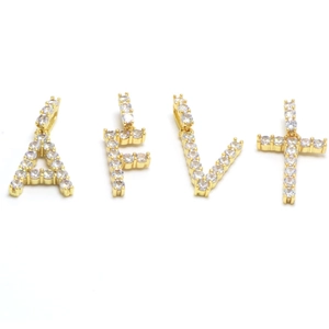 Close-up of gold iced out alphabet pendants A, F, V and a diamond cross pendant