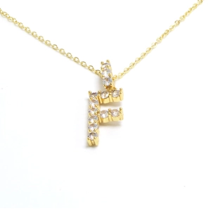 Detail of gold letter F pendant necklace paved with sparkling cubic zirconia stones