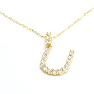 Macro shot of gold letter U pendant with shimmering pavé set clear crystals