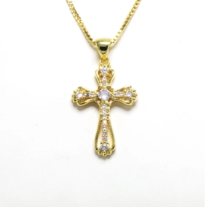 Macro detail of gold cross pendant with micro-paved zircons and a classic box chain