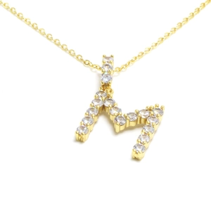 Macro shot of gold letter M pendant necklace with shimmering paved zircon crystals