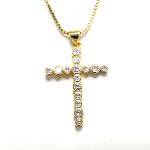 Detailed macro view of a gold cross pendant necklace with micro-paved cubic zirconia