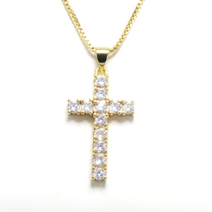 Macro shot of gold cross pendant with micro-paved zircons and classic box chain necklace