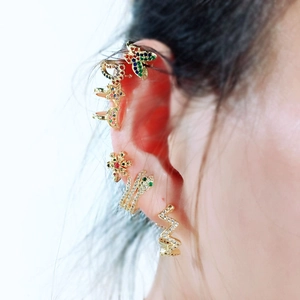 Close-up of golden multi-piece ear cuff and stud set with colorful zircons on ear