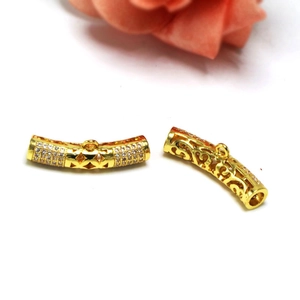 Macro shot of gold-plated curved connector beads with zircon pavé and hollow patterns