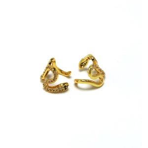 Close-up of golden snake-shaped ear clips with white zircons and green gemstone eyes