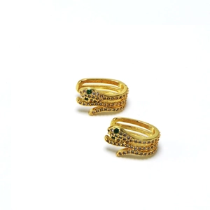 Macro shot of gold-plated snake ear cuff with white zircon and green gemstone eyes