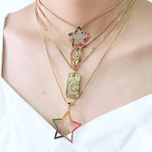 Detalle de collares dorados en capas con colgantes de luna estrella y circonitas de colores