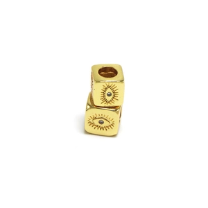Dettaglio macro di perline a cubo malocchio placcate oro con incisioni e foro centrale