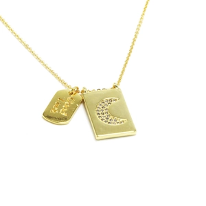 Detalle de colgante rectangular dorado con luna de circón y grabado Good Luck en cadena