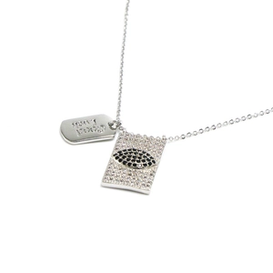 Detalle del colgante Evil Eye y la etiqueta Good Luck en una cadena de collar plateada