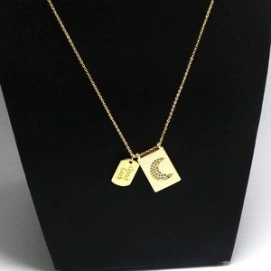 Detalle del colgante de luna dorado rectangular con grabado Good Luck y circonitas finas