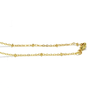 Close-up of golden O-chain necklace with decorative beads and secure lobster clasp