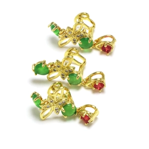 Detail von floralen Schmuckclips mit grünen Jade-Edelsteinen und roten Akzenten auf Gold