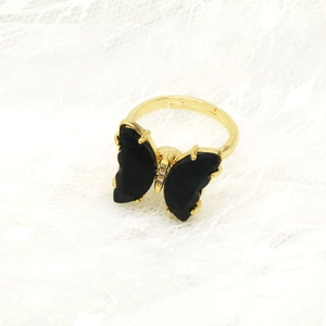 Detail eines goldenen Schmetterlingsrings mit schwarzen Kristallen und weißen Diamanten