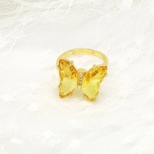 Nahaufnahme eines goldenen Schmetterlingsrings mit gelben Kristallen auf weißer Spitze