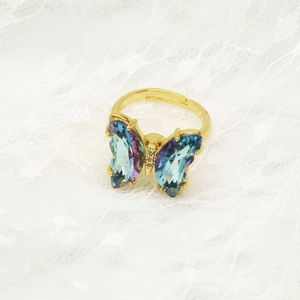 Detailaufnahme eines goldenen Schmetterlingsrings mit blau-violetten Kristallflügeln