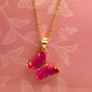 Dettaglio del ciondolo a farfalla rosa con cristalli marquise su una collana a catena dorata