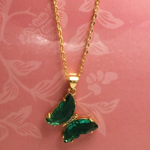 Dettaglio della collana dorata con ciondolo a farfalla in cristallo verde e piccoli diamanti