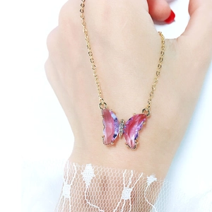 Detailed close-up of a butterfly pendant with purple gradient crystal wings on a gold chain