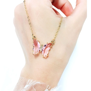 Detail of pink crystal butterfly pendant with sparkling diamonds on a gold necklace