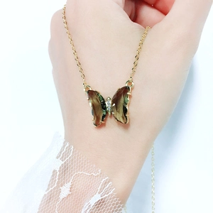Detailed macro of a gold butterfly necklace with gradient crystals and micro zircon stones