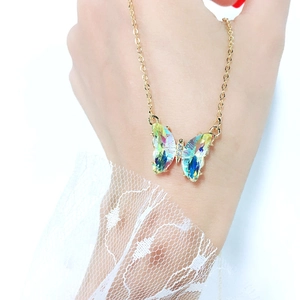 Close-up of a gold necklace featuring an iridescent butterfly pendant with sparkling rhinestones