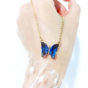 Detail of blue gradient crystal butterfly pendant with small diamonds on gold chain
