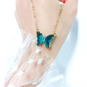 Detail of blue crystal butterfly pendant on gold chain with sparkling diamond accents