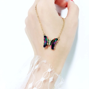 Detail of a gold butterfly necklace with gradient crystal wings and small zircon accent