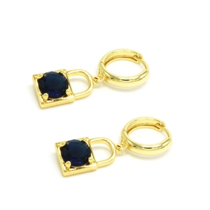 Détail des boucles d'oreilles cadenas dorées avec une pierre précieuse bleu foncé ronde
