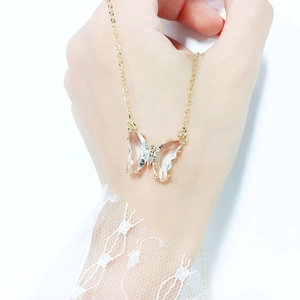 Elegant gold necklace with a transparent crystal butterfly pendant held by hand
