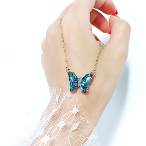 Detail of butterfly pendant necklace with blue faceted crystal and gold chain