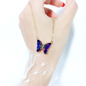 Detailed macro view of a colorful crystal butterfly pendant on a delicate gold chain necklace