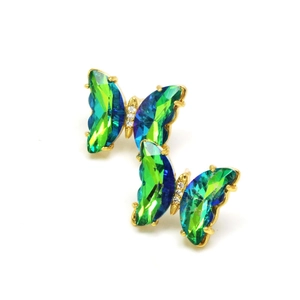 Macro detail of butterfly crystal earrings with vibrant green and blue gradient stones