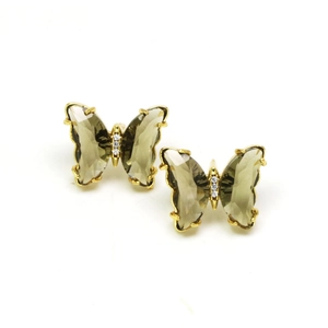 Macro detail of butterfly stud earrings with gold plating and dark brown crystals