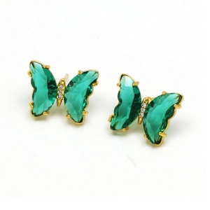 Macro detail of crystal butterfly stud earrings with green wings and gold metal plating