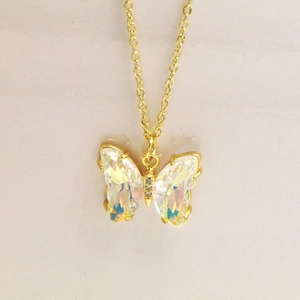 Vue détaillée du pendentif papillon doré avec des ailes en verre irisées et zircones