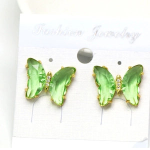 Macro view of crystal butterfly stud earrings with green wings and gold trim details