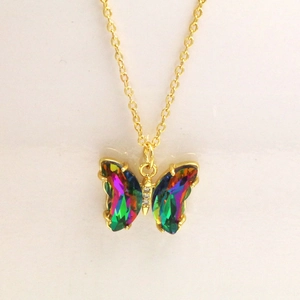 Détail macro du collier papillon avec des pierres de cristal et chaîne dorée